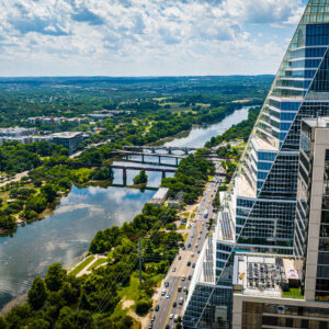 An aerial view of Austin with modern buildings and green trees along the riverbank. Texas, USA