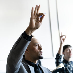 Business people in a seminar raising their hands