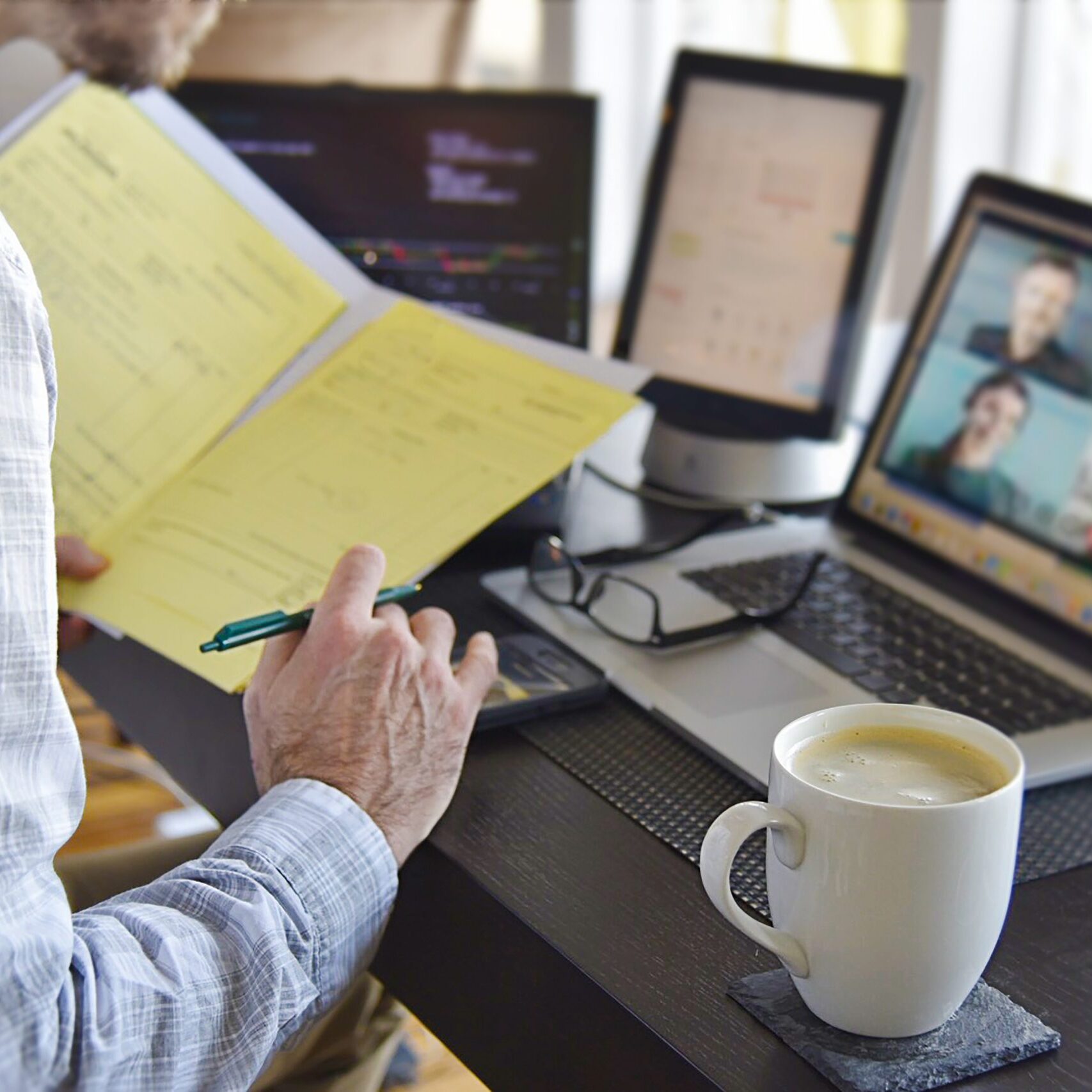 man looking at documents while in a virtual video chat meeting on computer